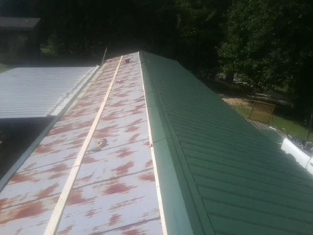 Old rusted panels beside newly installed green metal roofing — Wind Damage Roof Repair by Roofing Brothers in Shakopee