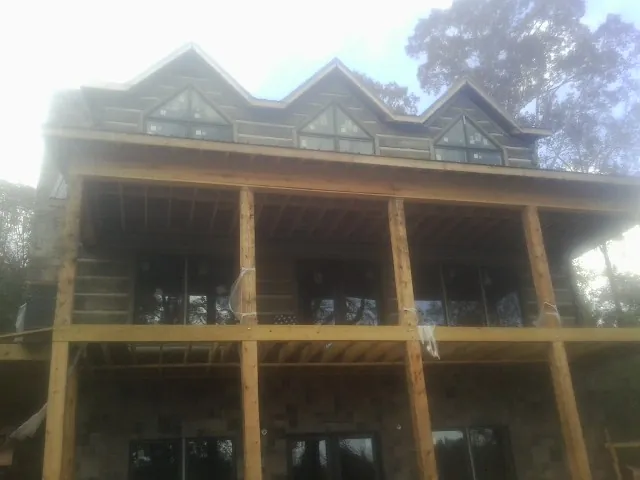Dormers and porch framing on a large log home under construction — Roof Coating work by our crew in Shakopee