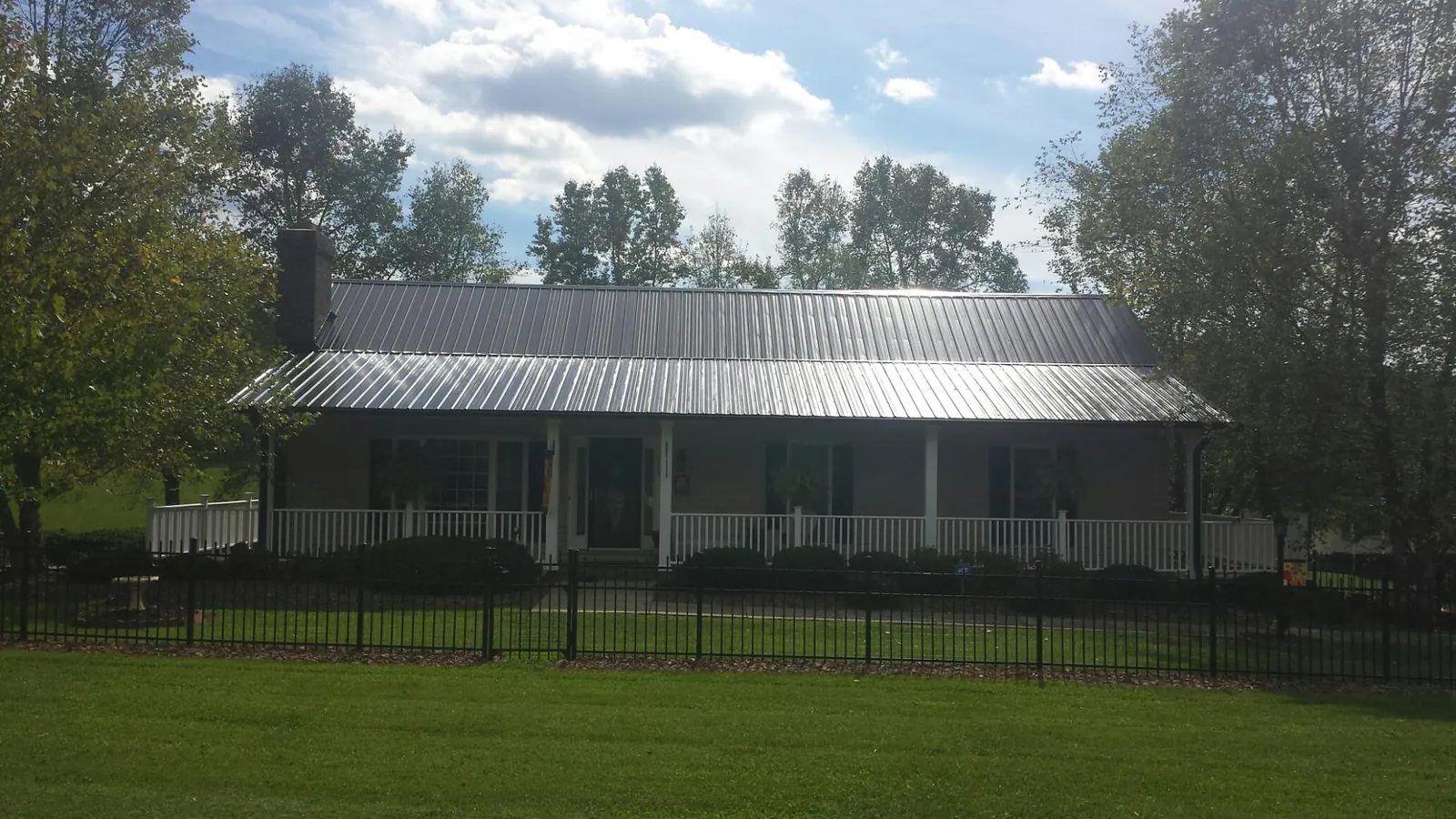 Gray metal roof on a brick ranch with a full width front porch — Gutter Guard Installation work by our crew in Shakopee