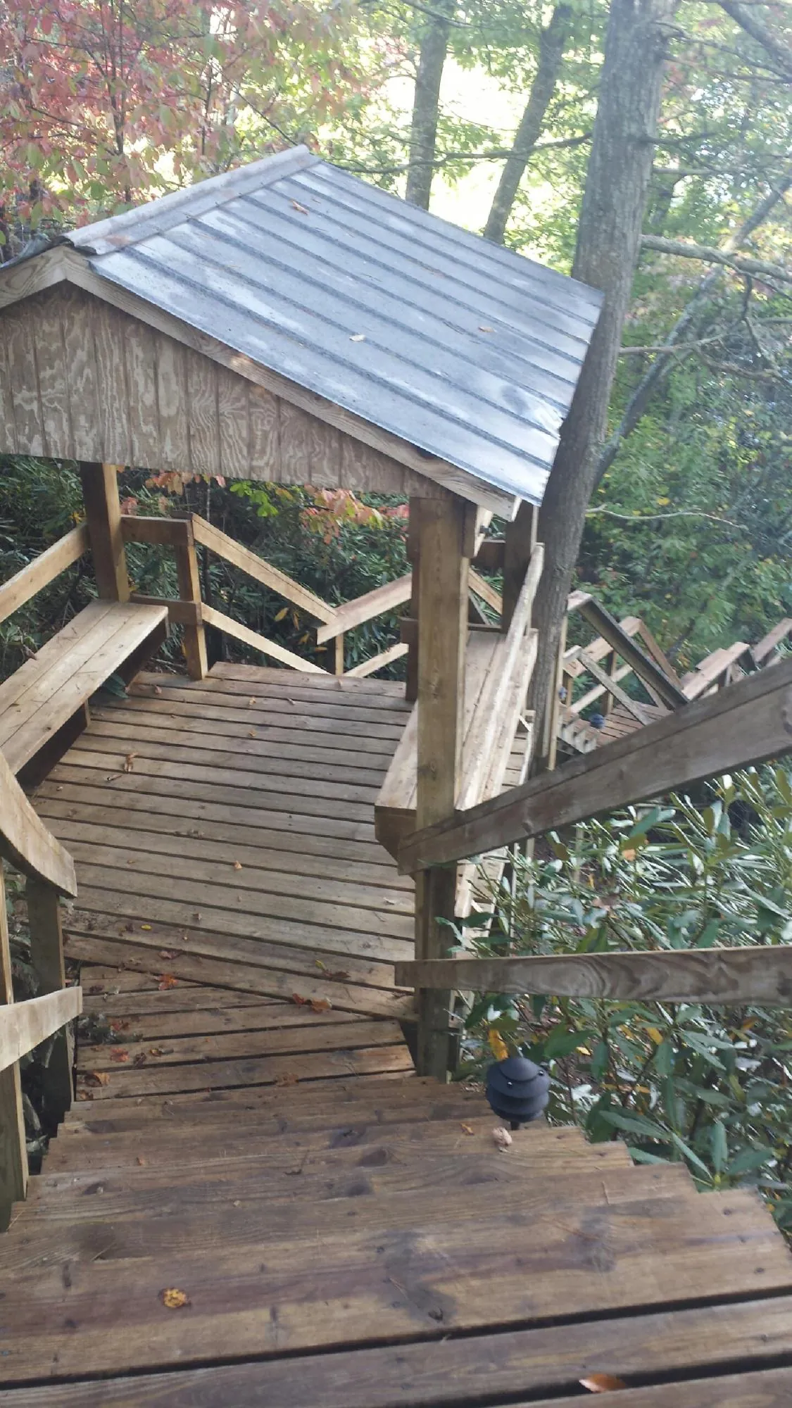 Metal roofed shelter over wooden steps on a wooded walkway — Skylight Repair & Installation work by our crew in Shakopee