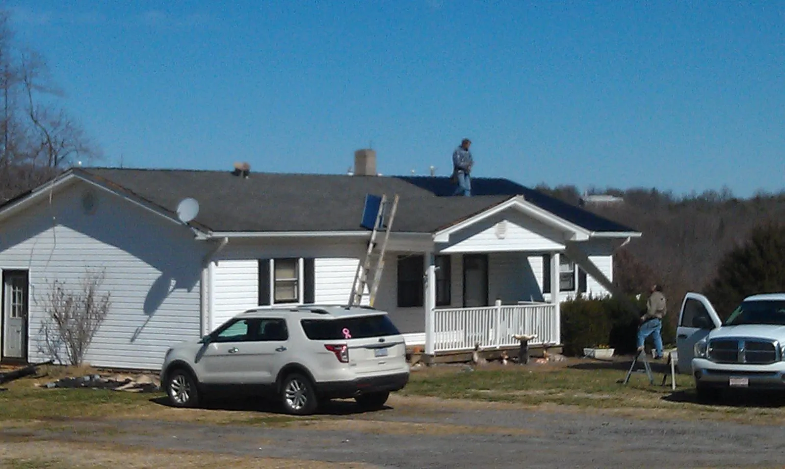 Roofers stripping shingles from a white ranch house roof in Shakopee