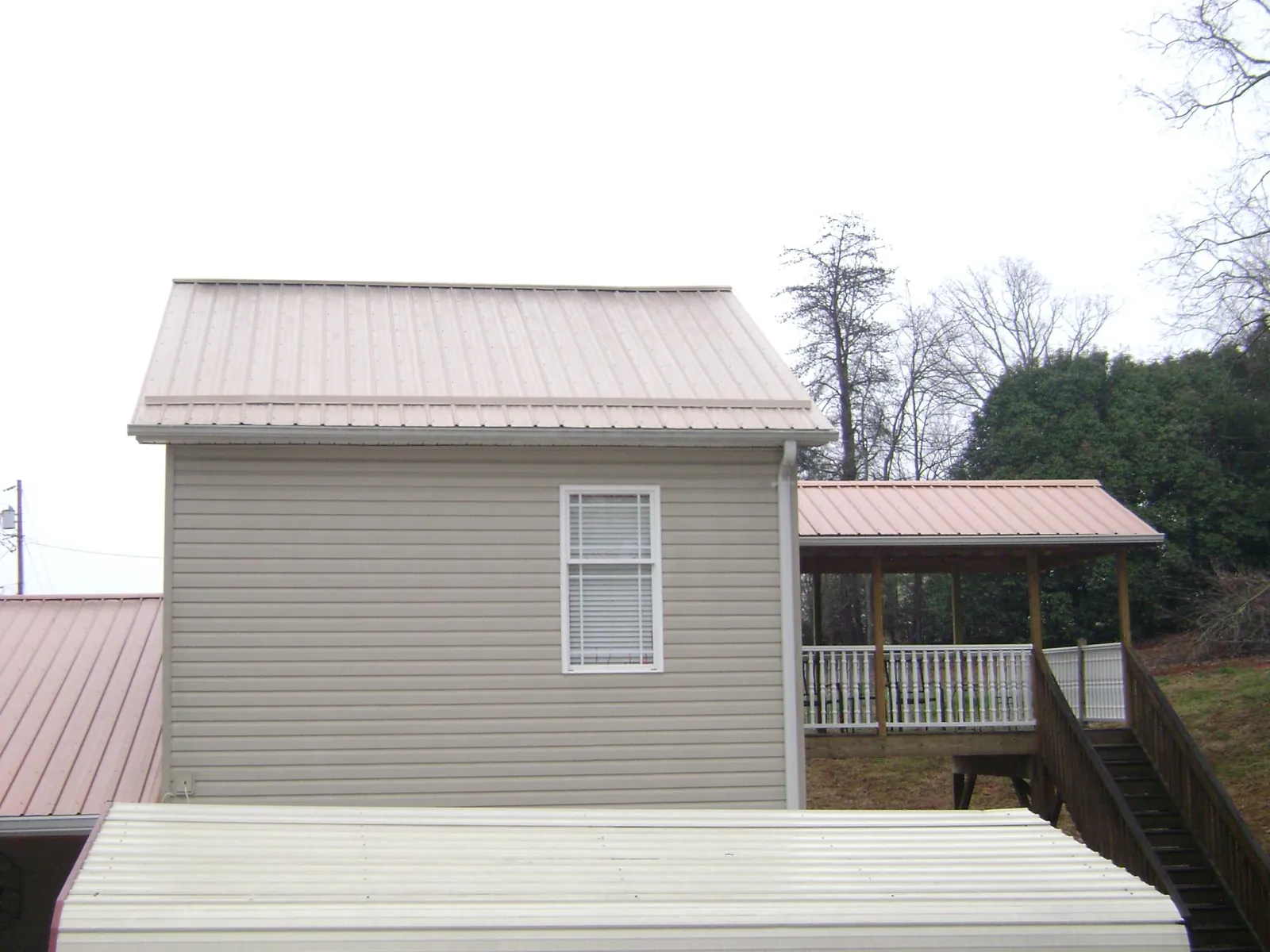 Tan metal roofs on a two story addition and attached porch, from a Roof Replacement job in Shakopee
