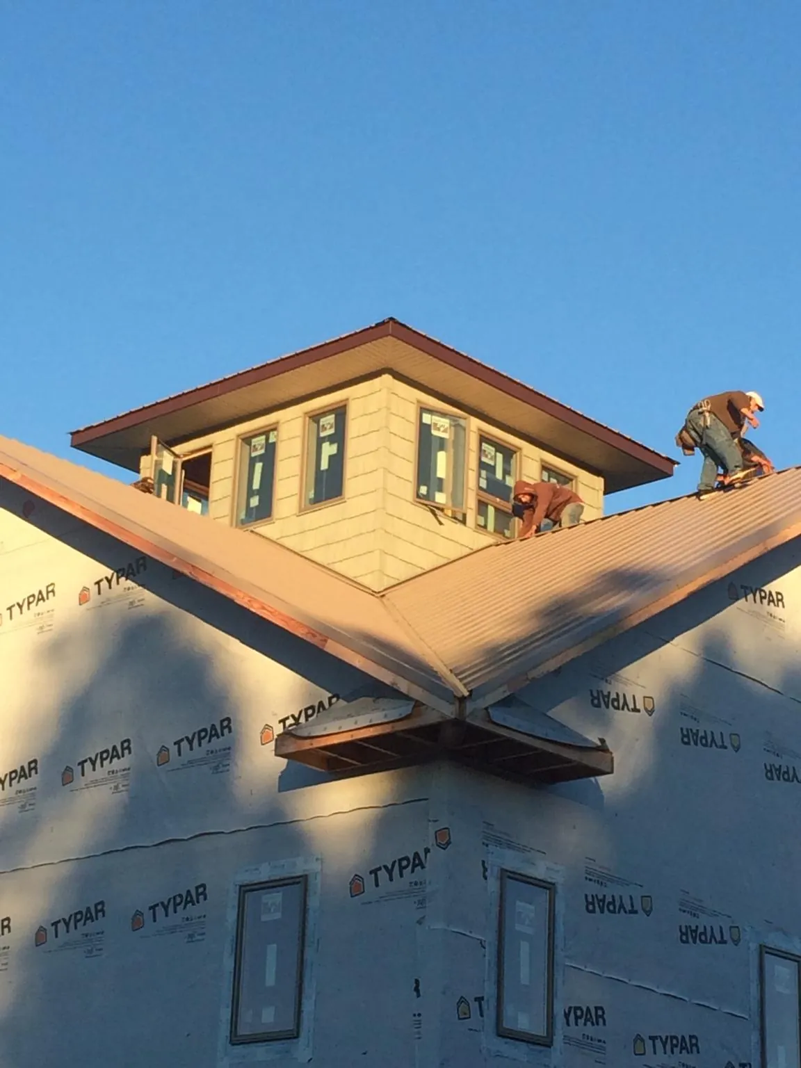Roofers working around a rooftop cupola on a new metal roof at sunset — Roof Waterproofing in Shakopee by Roofing Brothers